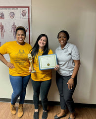 A funeral service camp participant with completion certificate, with Madeline Lyles and Dana Taylor