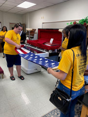 Two participants in funeral service camp folding American flag as would be done for a military funeral