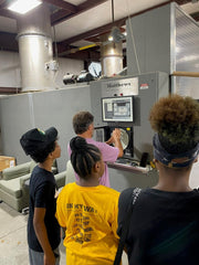 Funeral service camp participants learning about cremation. Several students pictured near cremation equipment and instructor