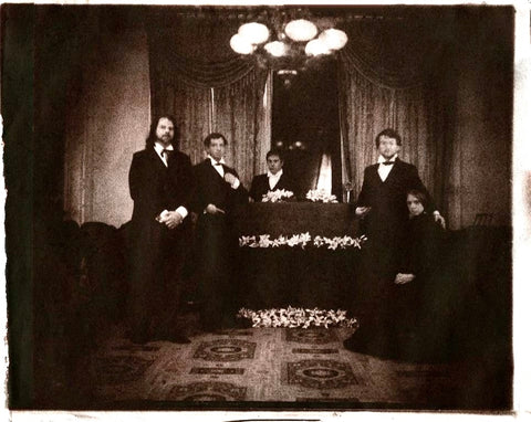 19th century photo: group of people standing around a casket in a home parlor