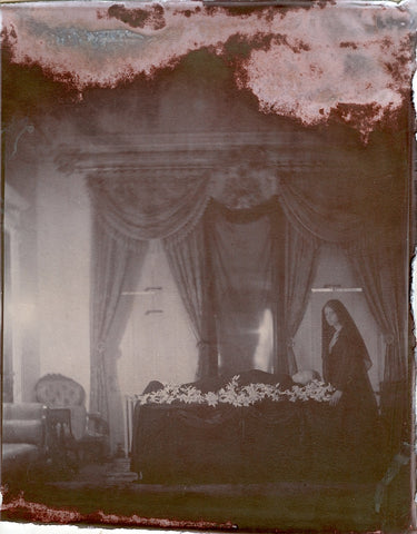 19th century photograph of woman standing next to casket in home's parlor