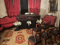 Recreation of 19th century funeral: Casket in home, "parlor" setting with chairs surrounding